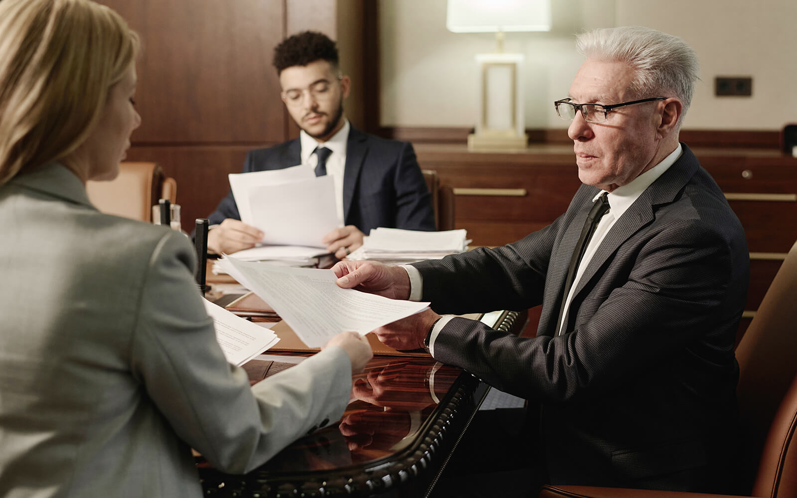 A man and woman in business attire, both attorneys, are seated at a table engaged in discussion.